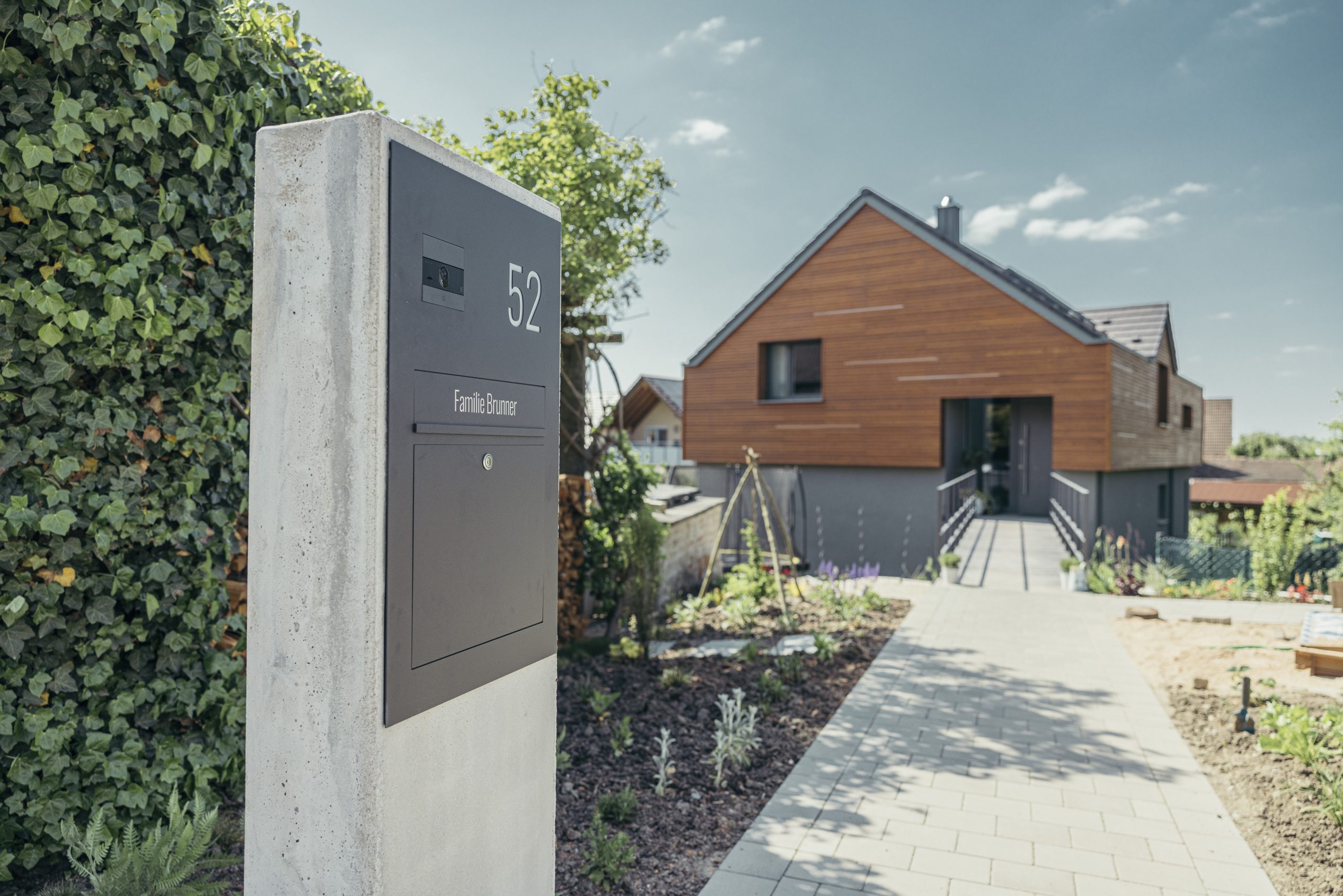 Freistehende HELLO Briefkastenanlage in einer Betonstele vor einem modernen Wohnhaus